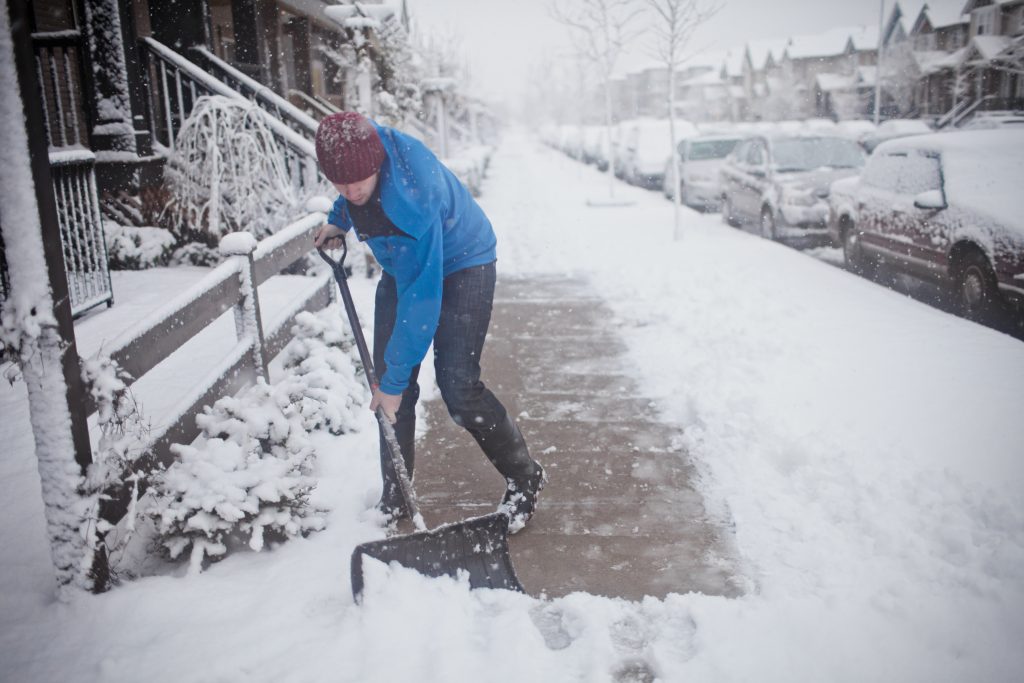 man shoveling snow off sidewalk