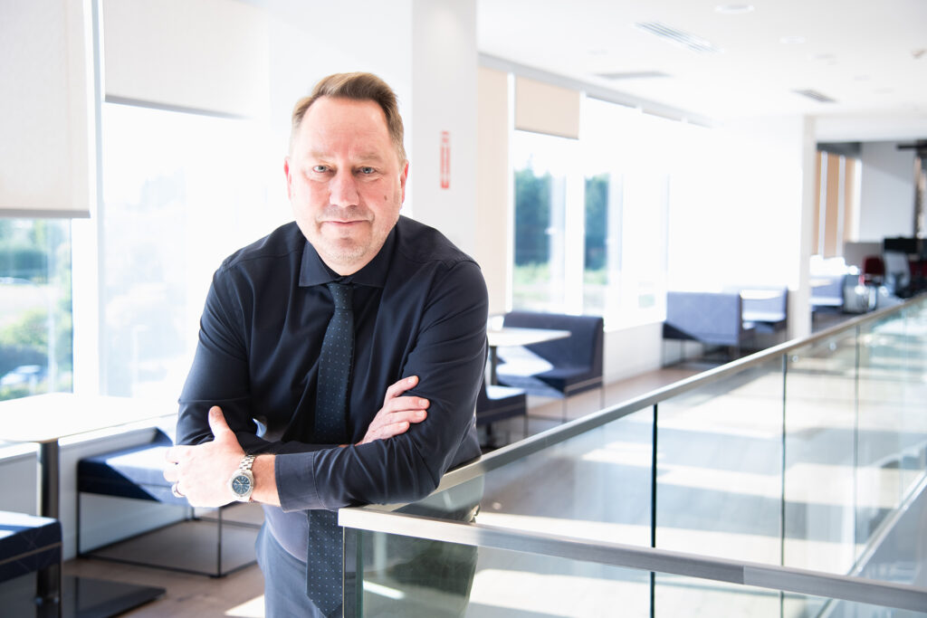 A man leans over a rail with arms crossed